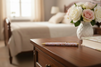 Wooden side table with a vase of flowers and books in a bedroom setting